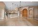 Open concept living room with travertine flooring, arched alcoves, neutral paint, and a view into the kitchen at 17557 Ohara Dr, Port Charlotte, FL 33948