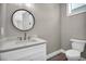 Well-lit half-bathroom featuring a round mirror, toilet, and hardwood floors at 16305 Branco Dr, Punta Gorda, FL 33955