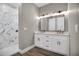 Bathroom with modern vanity, double sinks, designer mirror, and shower with marble-like tile at 16305 Branco Dr, Punta Gorda, FL 33955