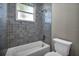 Bright bathroom with gray tiled shower, bathtub, and window with natural light at 16305 Branco Dr, Punta Gorda, FL 33955