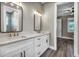 Primary bathroom with double sinks and mirrors, featuring white cabinets and hardwood floors at 16305 Branco Dr, Punta Gorda, FL 33955
