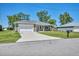 Single-story home featuring a well-kept lawn, a two-car garage, and mature trees at 16305 Branco Dr, Punta Gorda, FL 33955