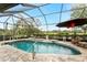 Screened-in pool area with an umbrella and view of a golf course at 8242 Lakeside Dr, Englewood, FL 34224