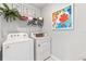 Bright laundry room with a modern washer and dryer set, storage shelf, and colorful wall art at 9446 Sunbeam Cir, Punta Gorda, FL 33950