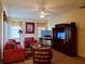 Comfortable living room with red furniture, TV, fan, and decorative window treatments at 1057 Staley St, Port Charlotte, FL 33952
