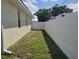 Narrow side yard featuring a green lawn and a tall white privacy fence offering seclusion at 1057 Staley St, Port Charlotte, FL 33952