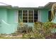 Home exterior with a large bay window framed by white shutters, complemented by lush green foliage and plants at 1845 Edison Dr, Englewood, FL 34224
