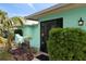 Inviting turquoise home featuring lush landscaping, a black-framed entryway and decorative exterior lighting fixture at 1845 Edison Dr, Englewood, FL 34224