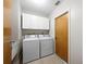 Functional laundry room featuring a washer, dryer, white cabinets and tile flooring at 1845 Edison Dr, Englewood, FL 34224