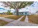 Street view of a light blue home with a well-manicured front yard, double driveway and mature shade tree at 3461 Normandy Dr, Port Charlotte, FL 33952
