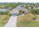 Aerial view of a home with a well-manicured lawn, a driveway, and mature landscaping at 18305 Wolbrette Cir, Port Charlotte, FL 33948