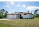 A modern home featuring a two-car garage, manicured lawn, and a minimalist landscape design at 5435 Montego Ln, Port Charlotte, FL 33981