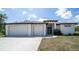 A front exterior of a modern home with a white facade, two-car garage, and meticulously kept lawn at 5435 Montego Ln, Port Charlotte, FL 33981