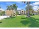 Charming single-Gathering home featuring a lush green lawn, attached two-car garage, and landscaped front yard with palm trees at 3663 Whippoorwill Blvd, Punta Gorda, FL 33950