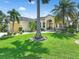 The front exterior boasts a well-manicured lawn and palm trees in this single Gathering home at 3663 Whippoorwill Blvd, Punta Gorda, FL 33950