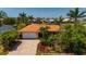 Charming home featuring an orange tile roof, lush landscaping, and a brick-paved driveway at 805 Brenda Ct, Punta Gorda, FL 33950