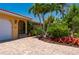Beautiful home with arched entry, red tile roof, brick driveway, and lush tropical landscaping creating a serene ambiance at 805 Brenda Ct, Punta Gorda, FL 33950