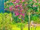 View of lush backyard featuring pink blossoms and a sandhill crane at 500 Woodstork Ln, Punta Gorda, FL 33982
