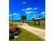 Scenic entrance to waterfront community featuring a sandy path, wooden fence, and tropical landscaping under a clear blue sky at 500 Woodstork Ln, Punta Gorda, FL 33982