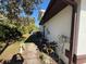 Side yard view of home with a white fence, tropical foliage, and sunny skies at 1438 Navigator Rd, Punta Gorda, FL 33983