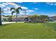Attractive home with a lush green lawn, complemented by palm trees and tasteful stone accents at 18395 Edgewater Dr, Port Charlotte, FL 33948