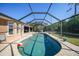 Spacious screened lanai featuring a sparkling pool and brick-paved deck at 18395 Edgewater Dr, Port Charlotte, FL 33948