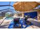 Inviting screened pool area with brick pavers, lounge chairs, and umbrella at 18395 Edgewater Dr, Port Charlotte, FL 33948