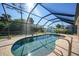 Sparkling screened-in pool with brick deck and lush landscaping beyond at 18395 Edgewater Dr, Port Charlotte, FL 33948