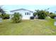 Wide shot of backyard with well-kept lawn, white home with windows, and palm trees at 6642 Acacia Ct, North Port, FL 34287