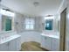 Bright bathroom featuring double sinks, white cabinets, stylish decor, and wood-look tile flooring at 6642 Acacia Ct, North Port, FL 34287