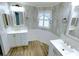 Bright bathroom featuring double sinks, white cabinets, stylish decor, and wood-look tile flooring at 6642 Acacia Ct, North Port, FL 34287