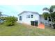 The backyard with a white home featuring vinyl siding and a sliding glass door with a lawn at 6642 Acacia Ct, North Port, FL 34287