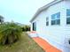 Exterior of the home featuring an orange walkway, vinyl siding, windows, and a sliding glass door at 6642 Acacia Ct, North Port, FL 34287