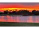 Vibrant sunset reflects off the calm lake, creating a serene and picturesque scene at 2275 Kenya Ln, Punta Gorda, FL 33983