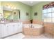 Bathroom featuring a garden tub, double sinks, and natural light from the window at 1020 Caliva St, North Port, FL 34286