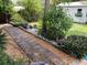 Lush backyard with a paver path featuring garden beds on both sides of the home at 18085 Wintergarden Ave, Port Charlotte, FL 33948