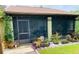 Home's screened-in porch surrounded by lush landscaping and a well manicured lawn at 18085 Wintergarden Ave, Port Charlotte, FL 33948
