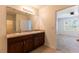 Bathroom with double sinks, cherry wood cabinets, and a view into the bedroom with a window at 3924 Candia Ave, North Port, FL 34286