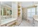Elegant bathroom featuring dual vanities, a makeup table, and a luxurious soaking tub with plantation shutters at 126 Peckham Sw St, Port Charlotte, FL 33952