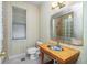 Bathroom with a wood vanity, a decorative mirror, a window, and a toilet at 126 Peckham Sw St, Port Charlotte, FL 33952