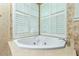 Close up of bathtub in tile surround with plantation shutters over windows at 126 Peckham Sw St, Port Charlotte, FL 33952