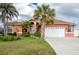 Charming coral home featuring a manicured lawn, palm trees, and a two-car garage at 126 Peckham Sw St, Port Charlotte, FL 33952