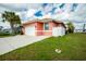 Single-story house featuring an attached garage, a well-manicured lawn, and mature palm trees at 126 Peckham Sw St, Port Charlotte, FL 33952