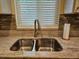 Close-up of the kitchen sink features granite countertops and decorative backsplash at 18938 Ayrshire Cir, Port Charlotte, FL 33948