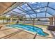 View of a screened-in pool area with a lounge chair and outdoor grill at 23239 Stelling Ave, Punta Gorda, FL 33980