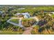 Aerial view of a grand home with circular drive, mature palms, playground and verdant landscape at 27320 Egret Pl, Punta Gorda, FL 33983
