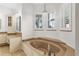 Luxurious bathroom featuring a soaking tub, stylish fixtures, and natural light from shuttered windows at 27320 Egret Pl, Punta Gorda, FL 33983
