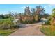 Long driveway framed by lush greenery and an ornate security gate enhances privacy and curb appeal at 27320 Egret Pl, Punta Gorda, FL 33983