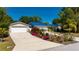 Charming single-story home with a blue roof, front yard landscaping, and a spacious driveway at 28482 Coco Palm Dr, Punta Gorda, FL 33982