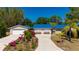 Charming single-story home with a blue roof, front yard landscaping, and a spacious driveway at 28482 Coco Palm Dr, Punta Gorda, FL 33982